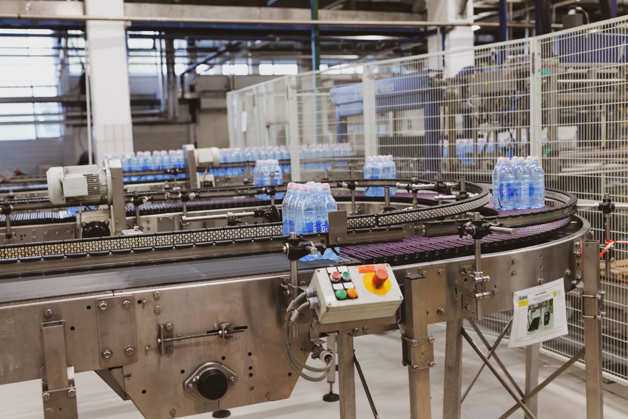Services Water bottles being processed on an automated conveyor in a modern factory setting.